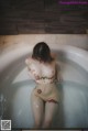 A naked woman sitting in a bathtub with a tattoo on her body.